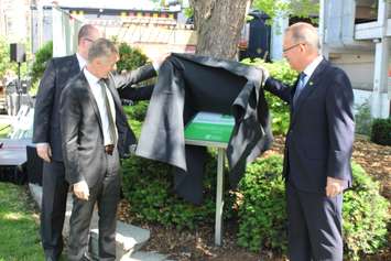 Windsor Mayor Drew Dilkens (left), University of Windsor President Alan Wildeman (left-center) and Mark Chauvin of TD Bank Group (right) unveil a new sign, marking the green space on Chatham St. as the TD Chatham Street Parkette, June 2, 2015. (Photo by Mike Vlasveld)