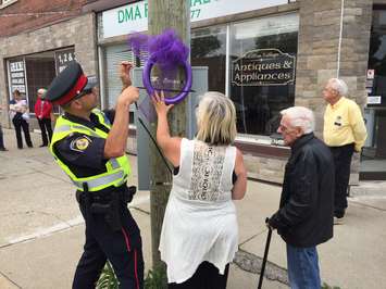 Sarnia Police Constable Nelson Amaral helps Sarnia-Lambton MADD President Natalie Leduc and Ralph MacIntosh place purple ribbons at Mitton and George St. May 24, 2017 (Photo by Melanie Irwin) 