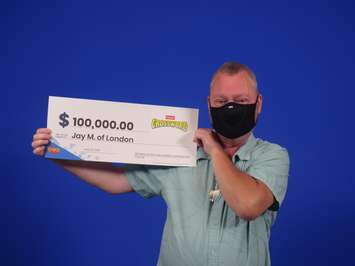 Londoner Jay Murr holding a cheque for a whopping $100,000 after winning on a $5 Instant Crossword ticket. Photo supplied by OLG.