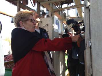 Kathleen Wynne prepared to push the button to empty tomato wagons at Highbury Canco. October 16, 2015 (Photo by Kevin Black)