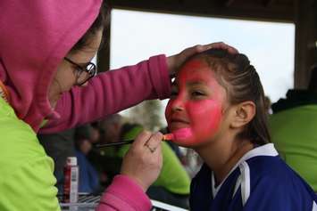 Eight-year-old Ayesha Lacelles waits patiently as a representative of Tek Savvy paints her face at Kingston Park on Monday. (photo by Michael Hugall)