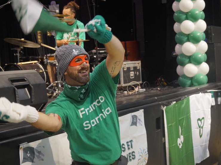A staff member waving flags at the Franco- Ontarian ceremony in Sarnia on September 25, 2025 (Photo by: Lindsay Newman/ Blackburn Media)