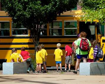 A group of children board a school bus. File photo courtesy of © Can Stock Photo / zerominusone