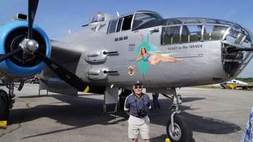 Retired Royal Canadian Air Force Major Noel Funge stands next to the B-25 