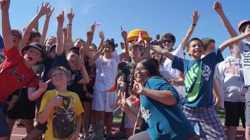 Mascot Pachi the porcupine poses with torchbearer Nathan Oliphant and elementary students at ASW track. June 16, 2015 (BlackburnNews.com Photo by Briana Carnegie)