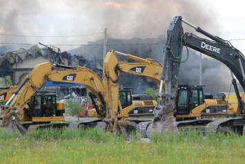 Behind equipment being used for its demolition, fire smolders at Windsor Raceway July 1, 2015. (Photo by Adelle Loiselle)