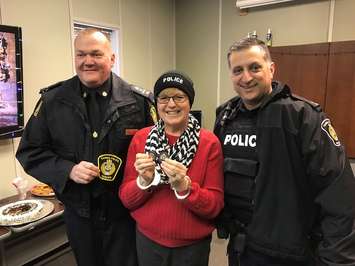 Sarnia Police Chief Norm Hansen (left) and Cst. John Sottosanti cuff Lee Michaels and present her with a community service medal during her retirement party. December 18, 2018. (Photo my Melanie Irwin, BlackburnNews)