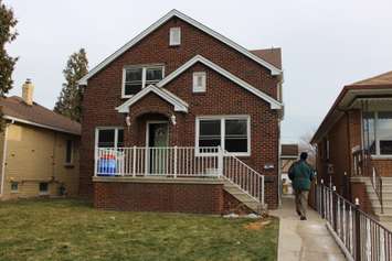 A Windsor police investigator walking alongside the duplex at 1566 Benjamin Ave. where the body of a 31-year-old has been found, December 11, 2014. (photo by Mike Vlasveld) 