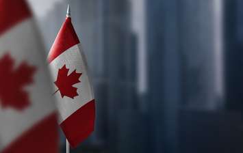 Small flags of canada on a blurry background of the city.© Can Stock Photo / butenkow