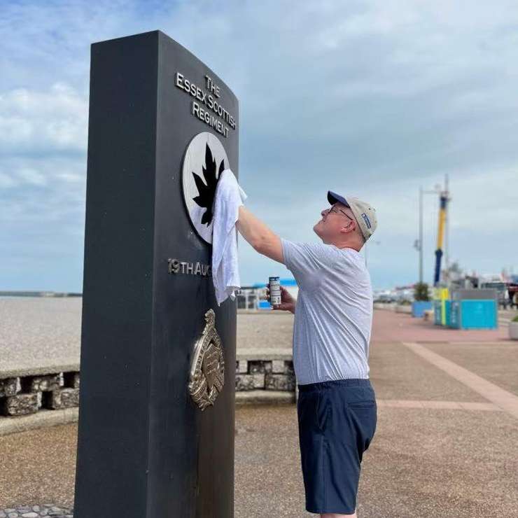 Windsor Mayor Drew Dilkens polishes the Dieppe monument with a cloth on August 17, 2023. Photo courtesy Mayor Drew Dilkens/Facebook.