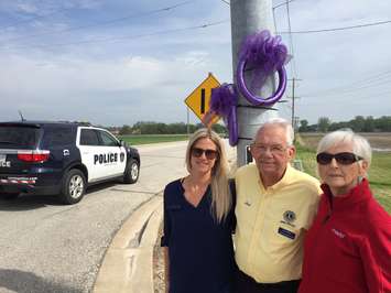 (left to right) Blair Abbey, Art Speed with the Lambton Drug Awareness Committee  and Mary Parkes (mother of Michael Parkes) place purple ribbons at Modeland Rd. and Michigan Ave. May 24, 2017 (Photo by Melanie Irwin)