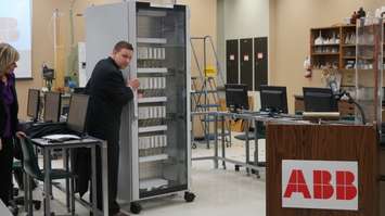 Lambton College Professor Chris Richardson turns the equipment around to reveal all of its sources. ABB donated eight computer systems. January 21, 2016 (BlackburnNews.com Photo by Briana Carnegie)