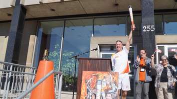 Wes Harding holds the first torch high at Sarnia Pan Am Games celebration outside City Hall June 16, 2015 (BlackburnNews.com Photo by Briana Carnegie)