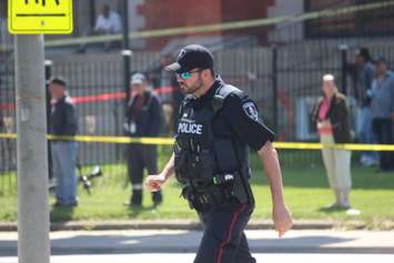 A Windsor police officer controlling a crowd of people who have come to watch firefighters battle a fire on Wyandotte St. E, May 23, 2016.  (Photo by Adelle Loiselle)
