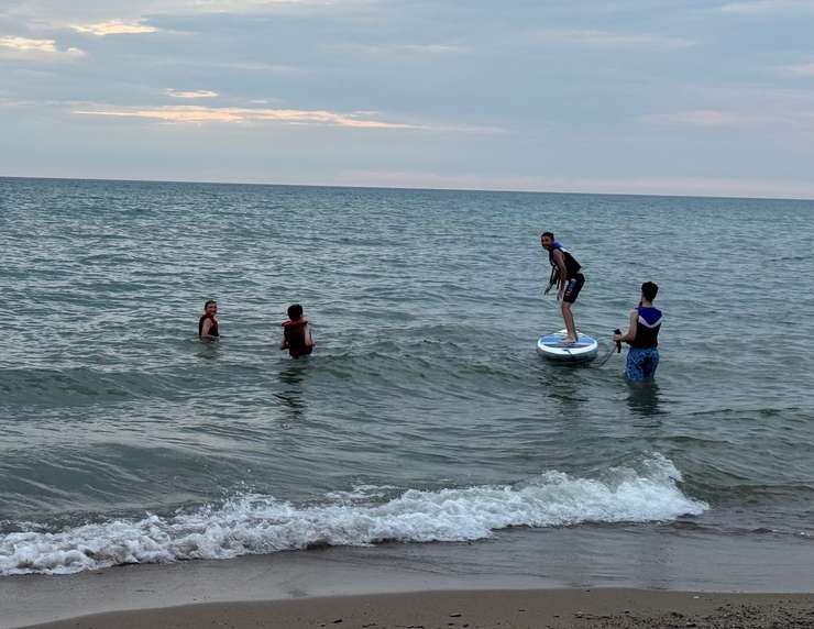 Children in life jackets play with a paddle board on Lake Huron. July, 2025. Blackburn Media photo by Melanie Irwin