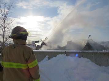 A London firefighter looks on as an aerial truck pumps water on a fire at Hully Gully on Wharncliffe Rd., December 28, 2017. (Photo by Miranda Chant, Blackburn News)