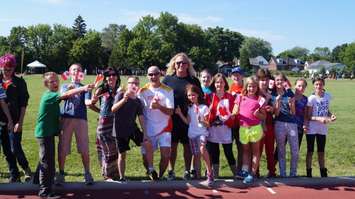 Torchbearer Wes Harding poses with elementary students at Pan Am Games celebration at ASW track June 16, 2015 (BlackburnNews.com Photo by Briana Carnegie)