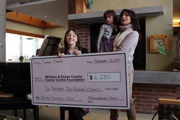 Lauren Baillargeon holds a cheque she and her family are donating to the Windsor Essex County Cancer Centre Foundation. Also in the pciture are Lauren's little sister and Houida Kassem of the foundation. (Photo by Mike Vlasveld)