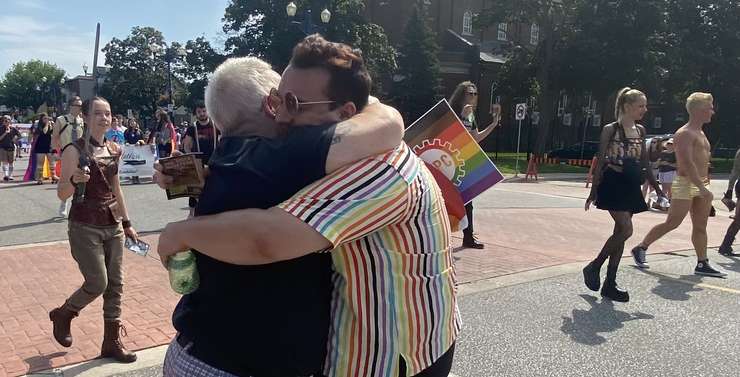 Parade goers share a hug, August 13, 2023 (Photo courtesy of Adelle Loiselle, Blackburn Media)
