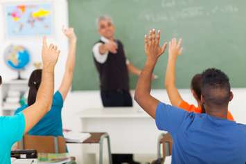 Group of students with hands up in classroom during a lesson © Can Stock Photo / michaeljung