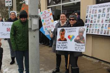 Demonstrators hold up signs at a rally outside the Ministry of Children, Community and Social Services field office in Windsor, February 14, 2019. Photo by Mark Brown/Blackburn News.