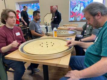 Al Little (right) lines up a shot against Grant Flick (left) at the Frosty Flick crokinole tournament at Turns and Tales in Chatham. Photo by Matt Weverink. 