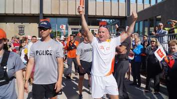 Wes Harding holds the first torch high at Sarnia Pan Am Games celebration outside City Hall June 16, 2015 (BlackburnNews.com Photo by Briana Carnegie)