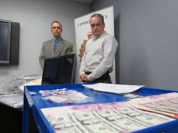 London Police Detective Constable Paul Ferreira and Detective Sergeant Blair Harvey show off the counterfeiting equipment and money seized in a recent raid on Highbury Ave. (Photo by Miranda Chant, Blackburn News)