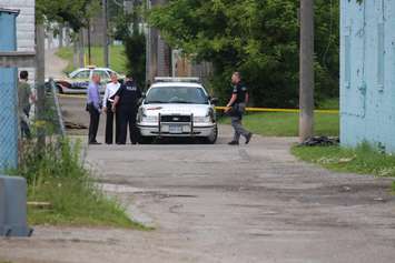 Detectives canvass an alley in the 500 block of Brant St. near where the body was discovered. (Photo by Jason Viau)