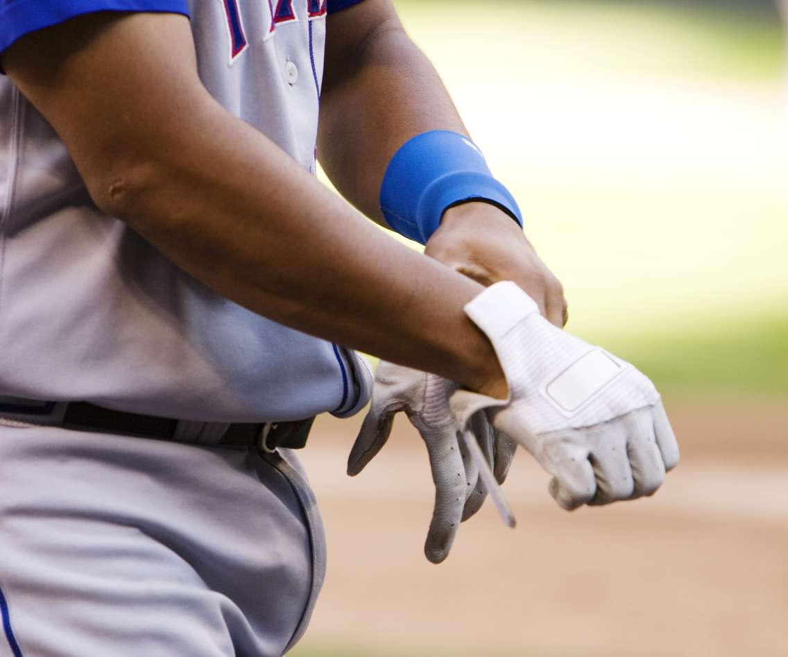 Professional baseball player putting on gloves. @Can Stock Photo/searagen