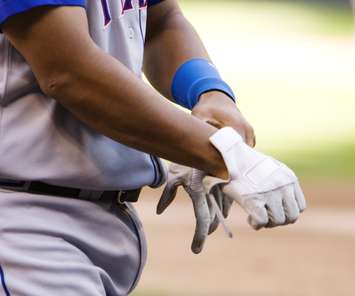 Professional baseball player putting on gloves. @Can Stock Photo/searagen