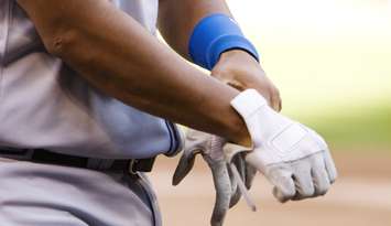 Professional baseball player putting on gloves. @Can Stock Photo/searagen