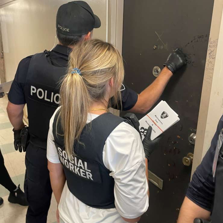 A Windsor police officer knocks on the door of a unit at an apartment building on Glengarry Avenue, accompanied by a social worker. Photo courtesy Windsor Police Service/X.