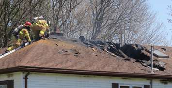 London firefighters douse hot spots on the roof of 25 Glass Ave. following a fire at the home, May 8, 2018. (Photo by Miranda Chant, Blackburn News)