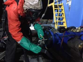 Edward Primeau, an industrial hygienist with the Coast Guard Atlantic Strike Team,  collects a sample of water product mixture that was pumped from the sunken barge Argo during lighting operations, Nov. 24, 2015. Samples are collected while the product is being removed to identify the contents of the barge’s tanks. (U.S. Coast Guard photo by Kurt Kollar, Ohio EPA)