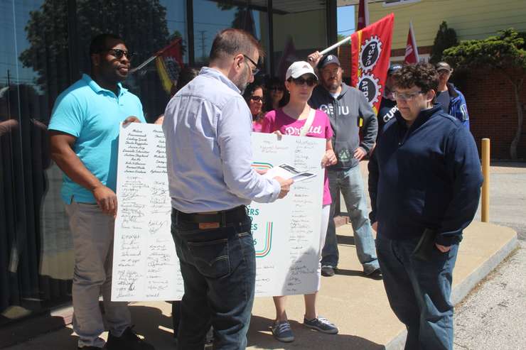 CUPE Local 8916 President Shaun Steven, right, hands over petition documents to Mike Lesperance, assistant to Windsor-Tecumseh MPP Andrew Dowie, in Windsor, May 8, 2024. Photo by Mark Brown/WindsorNewsToday.ca.