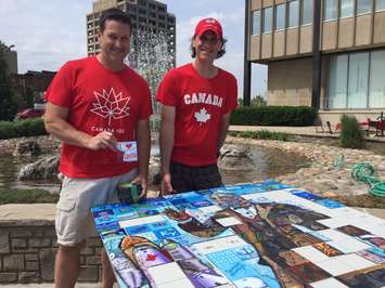 Canada 150 Mural Mosaic producers Phil Alain and Paul Lavoie show the progress of Sarnia's project. June 13, 2017 (Photo by Melanie Irwin)