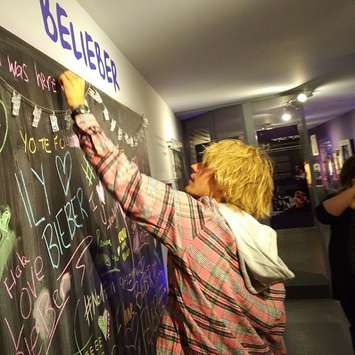 Justin Bieber signing the chalk board which fans have signed when visiting the display in Stratford. (Picture courtesy of John Kastner)