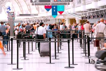 Passengers lining up at check-in counter at the modern international airport. © Can Stock Photo / Elenathewise