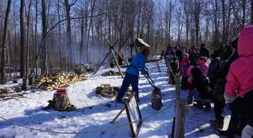 Melissa Gill, Conservation Education Technician, teaching visitors the different methods of maple syrup production used throughout history. March 2018. (Photo by St. Clair Region Conservation Authority)