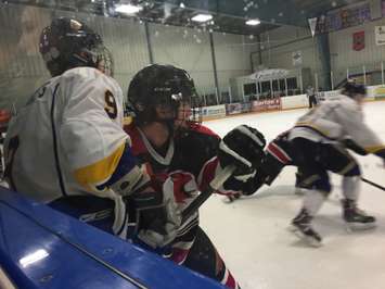 A Walkerton Hawk holds a Wingham player up against the boards during Game 1 of the 2014-2015 Western Jr. C Final.  Photo by Marty Thompson.