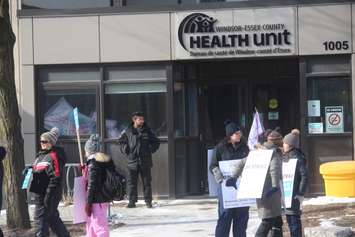 A security guard stands outside the Windsor-Essex County Health Unit as picketers walk on March 8, 2019. Photo by Mark Brown/Blackburn News.