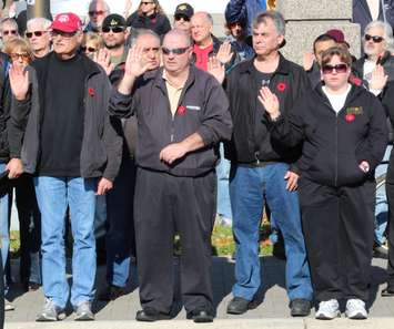 Attendees at the Remembrance Day ceremonies at the Windsor cenotaph, raise their right hands and pledge allegiance to Canada, November 11, 2014. (photo by Mike Vlasveld) 