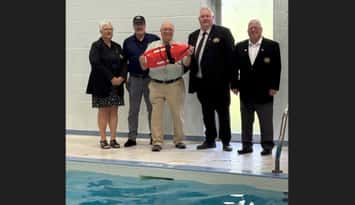 Sarnia-Lambton MPP Bob Bailey holds a lifeguard rescue buoy at the Moore Sports Complex when awarding $1 million for the facility to council members. July, 2025. Image courtesy of the Mooretown Sports Complex Facebook page.