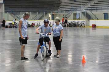 Learning how to ride a bike with the help of volunteers at the iCan Bike Camp in Chatham. July 13, 2016. (Photo by Natalia Vega)