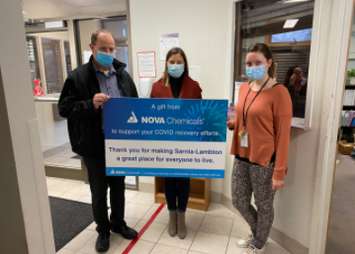 A member of the Women's Interval Home Home accepts a donation from NOVA Chemicals on Giving Tuesday. Image courtesy of NOVA Chemicals.