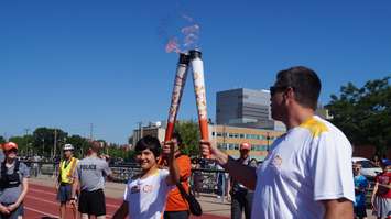 Torchbearer Nathan Oliphant passes on the flame to last runner, Joel Skinner for the Sarnia Pan Am torch run June 16, 2015 (BlackburnNews.com Photo by Briana Carnegie)