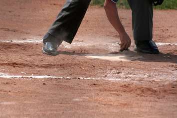 An umpire dusts off home plate. © Can Stock Photo / ca2hill