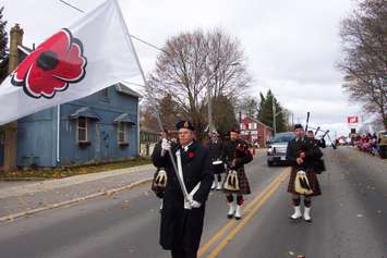 A colour guard accompanied by a pipe band marching to the Mount Forest Remembrance Day ceremony. (Photo by Campbell Cork)