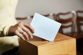 Woman places a ballot into a ballot box. © Can Stock Photo / gina_sanders